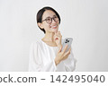 一位中年婦女在白色背景下使用智慧型手機進行想像。 142495040