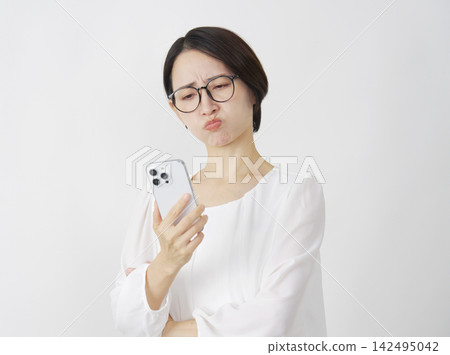 中年婦女看著手機，顯得很生氣（白色背景） 142495042
