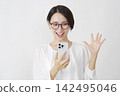 一位中年婦女看著她的智慧型手機，臉上露出驚訝的笑容（白色背景）。 142495046
