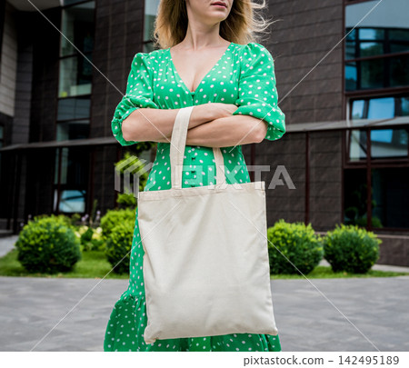 Young beautyful woman with linen eco bag on city background. Young beautyful woman with linen eco bag on city background. 142495189