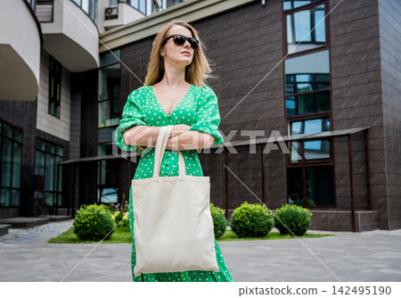 Young beautyful woman with linen eco bag on city background. Young beautyful woman with linen eco bag on city background. 142495190
