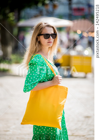 Young beautyful woman with yellow linen eco bag on city background. Young beautyful woman with yellow linen eco bag on city background. 142495218