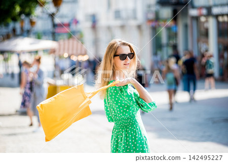 Young beautyful woman with yellow linen eco bag on city background. 142495227