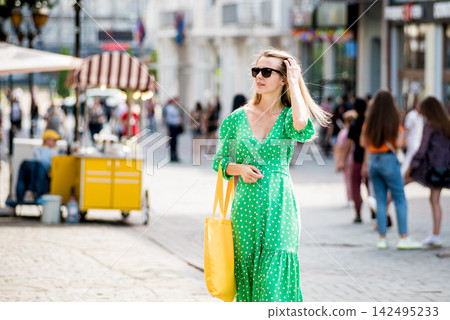 Young beautyful woman with yellow linen eco bag on city background. Young beautyful woman with yellow linen eco bag on city background. 142495233