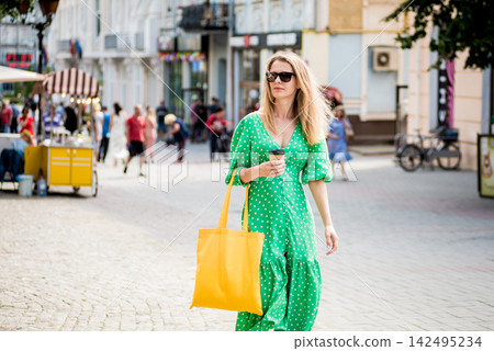 Young beautyful woman with yellow linen eco bag on city background. 142495234