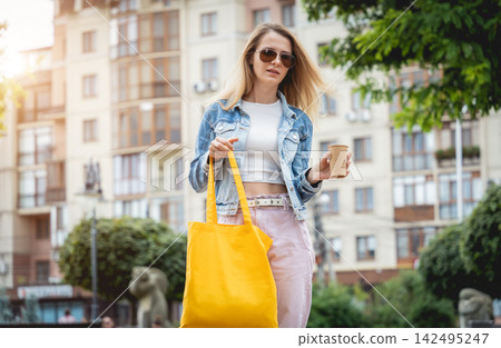 Young beautiful woman with linen eco bag on city background. Young beautiful woman with linen eco bag on city background. 142495247