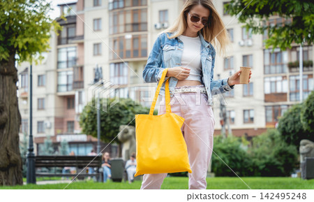 Young beautiful woman with linen eco bag on city background. Young beautiful woman with linen eco bag on city background. 142495248