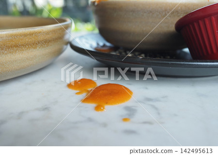 Food sauce spills on a table near bowls and plates 142495613
