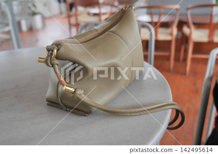 Handbag resting on a table in a cafe setting 142495614