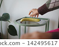 Hand reaching for banana on small table 142495617