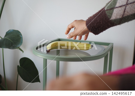 Hand reaching for banana on small table 142495617