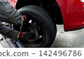 The hands of a car mechanic removing a car tire 142496786