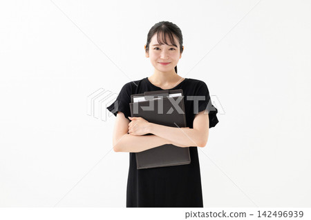 一名女子手持活頁夾,站在白色背景前。 一名女子手持活頁夾,站在白色背景前。 142496939