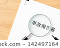 Close-up of the accident report, magnifying glass, and ballpoint pen. 142497164