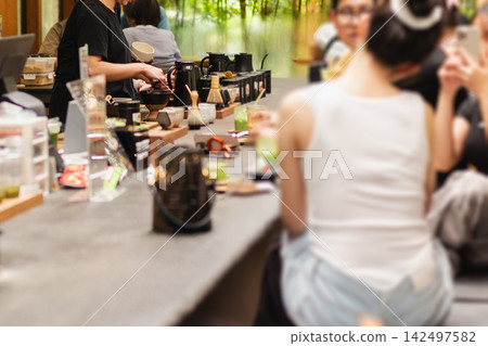 Customers sitting at counter while a barista prepares Japanese matcha green tea . 142497582