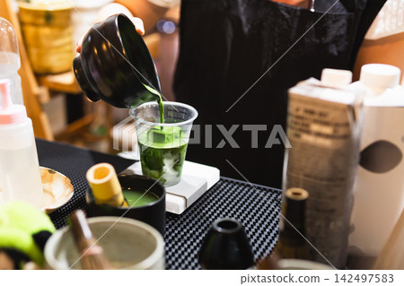 Barista pouring green matcha tea in a take away glasses with iced. Barista pouring green matcha tea in a take away glasses with iced. 142497583