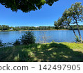 A lake surrounded by a blue sky and lush green trees (Summer leisure/nature background material) 142497905
