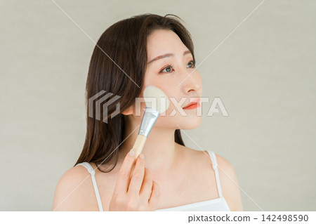 一張女性用化妝刷給臉頰上妝的美麗照片。 一張女性用化妝刷給臉頰上妝的美麗照片。 142498590