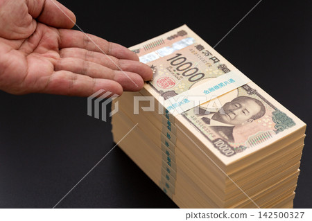 男人手裡拿著一疊1000萬日元的鈔票。 男人手裡拿著一疊1000萬日元的鈔票。 142500327