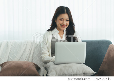Young Asian Woman Studying Online with Laptop, Tablet, Smartphone and Headphones at Home, Adult Education and E-Learning 142500510