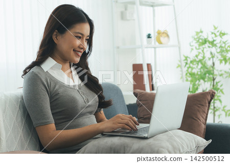 Young Asian Woman Studying Online with Laptop, Tablet, Smartphone and Headphones at Home, Adult Education and E-Learning 142500512