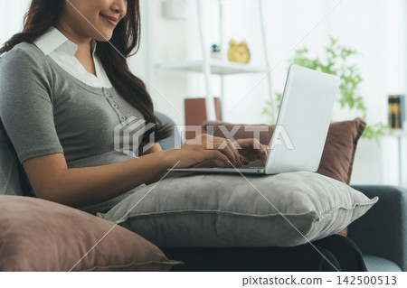 Young Asian Woman Studying Online with Laptop, Tablet, Smartphone and Headphones at Home, Adult Education and E-Learning 142500513