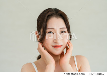 A beautiful, mature woman smiles with her hand on her cheek - Beauty and skincare image A beautiful, mature woman smiles with her hand on her cheek - Beauty and skincare image 142500867
