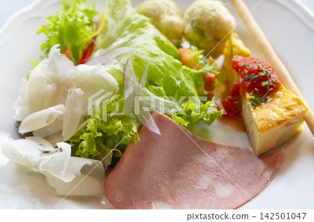 An Italian appetizer plate featuring prosciutto, cheese, and colorful vegetables. An Italian appetizer plate featuring prosciutto, cheese, and colorful vegetables. 142501047