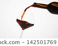 Red wine pouring into tilted wineglass from bottle. 142501769