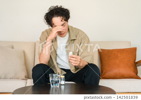 一位中年男子看著體溫計,因身體不適而感到不安——發燒和體溫檢測的畫面。 一位中年男子看著體溫計,因身體不適而感到不安——發燒和體溫檢測的畫面。 142501839