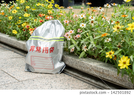 Flowers in the flowerbed and disaster preparedness supplies for emergencies and earthquakes. Flowers in the flowerbed and disaster preparedness supplies for emergencies and earthquakes. 142501892
