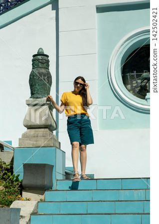 Young woman standing on sunny steps beside historic architecture in summer 142502421