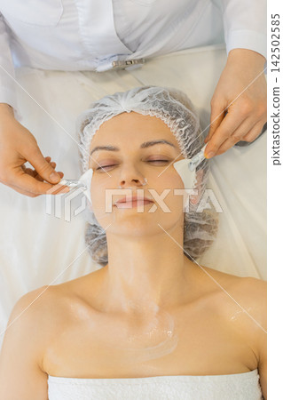 Cosmetologist applies cream and foaming skincare product on woman face in beauty clinic treatment Cosmetologist applies cream and foaming skincare product on woman face in beauty clinic treatment 142502585
