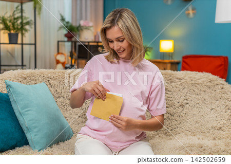 Pregnant woman writing message to baby placing envelope on belly imagining future reading warm hope Pregnant woman writing message to baby placing envelope on belly imagining future reading warm hope 142502659