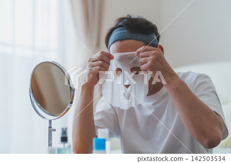 A 40-year-old man applying a sheet mask to his face - Men's beauty A 40-year-old man applying a sheet mask to his face - Men's beauty 142503534