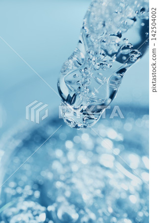 Clear liquid with air bubbles flowing from scientific dropper against blue background Clear liquid with air bubbles flowing from scientific dropper against blue background 142504002