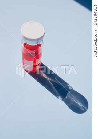 Clear glass vial with red solution for vaccine or drug development on blue background Clear glass vial with red solution for vaccine or drug development on blue background 142504014