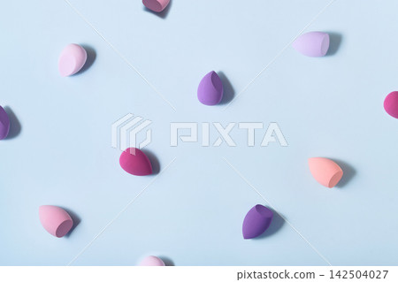 Colorful makeup sponges creating pattern on blue background Colorful makeup sponges creating pattern on blue background 142504027