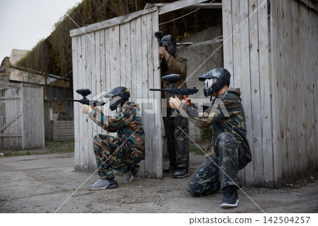 An armed group of several soldiers practice with weapons on a training field together 142504257