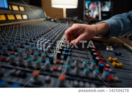Detailed view of operators manipulating analog mixing knobs during session Detailed view of operators manipulating analog mixing knobs during session 142504278