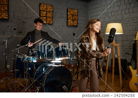 Caucasian girl singing into vintage microphone with dynamic band cooperation 142504288