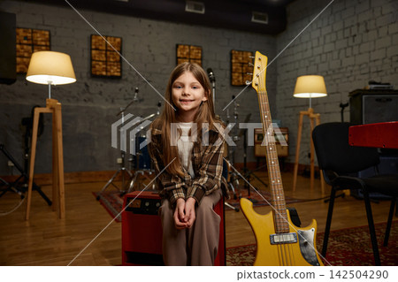 Young player happily preparing her lively yellow electric guitar for performance Young player happily preparing her lively yellow electric guitar for performance 142504290