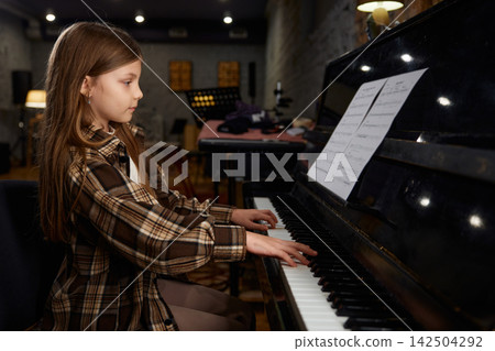 Teenage girl in cozy studio passionately performing with sheet music and warm lighting Teenage girl in cozy studio passionately performing with sheet music and warm lighting 142504292
