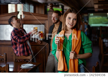 Happy woman in cozy bar observing friends celebrating with lively chatter 142504336