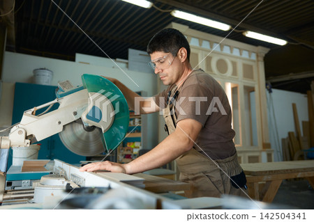 Carpenter cutting wood on miter saw Carpenter cutting wood on miter saw 142504341