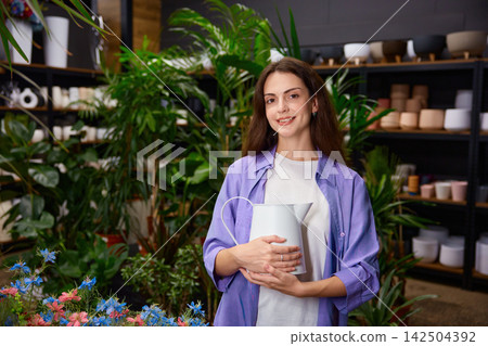 Woman holding ceramic vase in boutique studio with shelves behind Woman holding ceramic vase in boutique studio with shelves behind 142504392