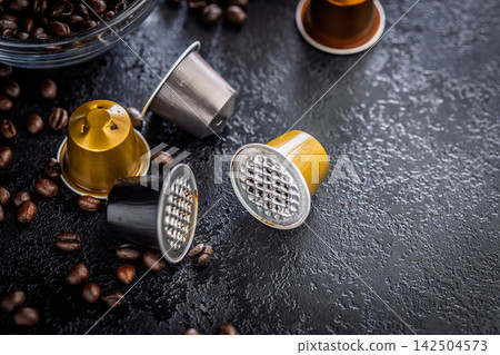 Used Coffee Capsules and Roasted Beans on Dark Textured Surface for Espresso Brewing Used Coffee Capsules and Roasted Beans on Dark Textured Surface for Espresso Brewing 142504573