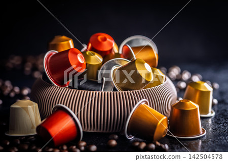 Colorful Coffee Pods And Capsules In A Bowl With Scattered Coffee Beans On Dark Background Colorful Coffee Pods And Capsules In A Bowl With Scattered Coffee Beans On Dark Background 142504578