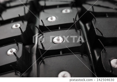 Studded winter tire tread closeup with metal spike detail. Studded winter tire tread closeup with metal spike detail. 142504630