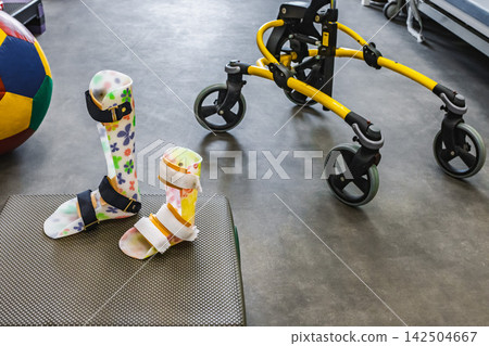 Plastic orthoses and walkers enable a child with a disability to improve walking skills during rehabilitation in a bright rehab medical center Plastic orthoses and walkers enable a child with a disability to improve walking skills during rehabilitation in a bright rehab medical center 142504667